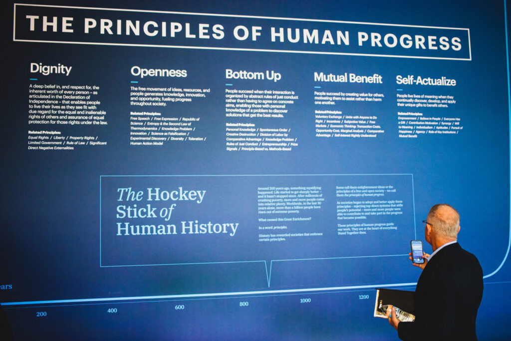 A man looking at an event exhibit articulating the principles of human progress