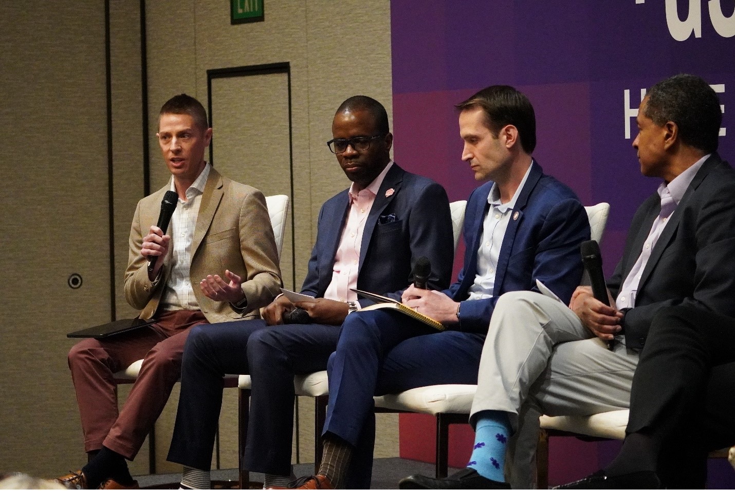 A group of individuals speaking on a panel at a conference.