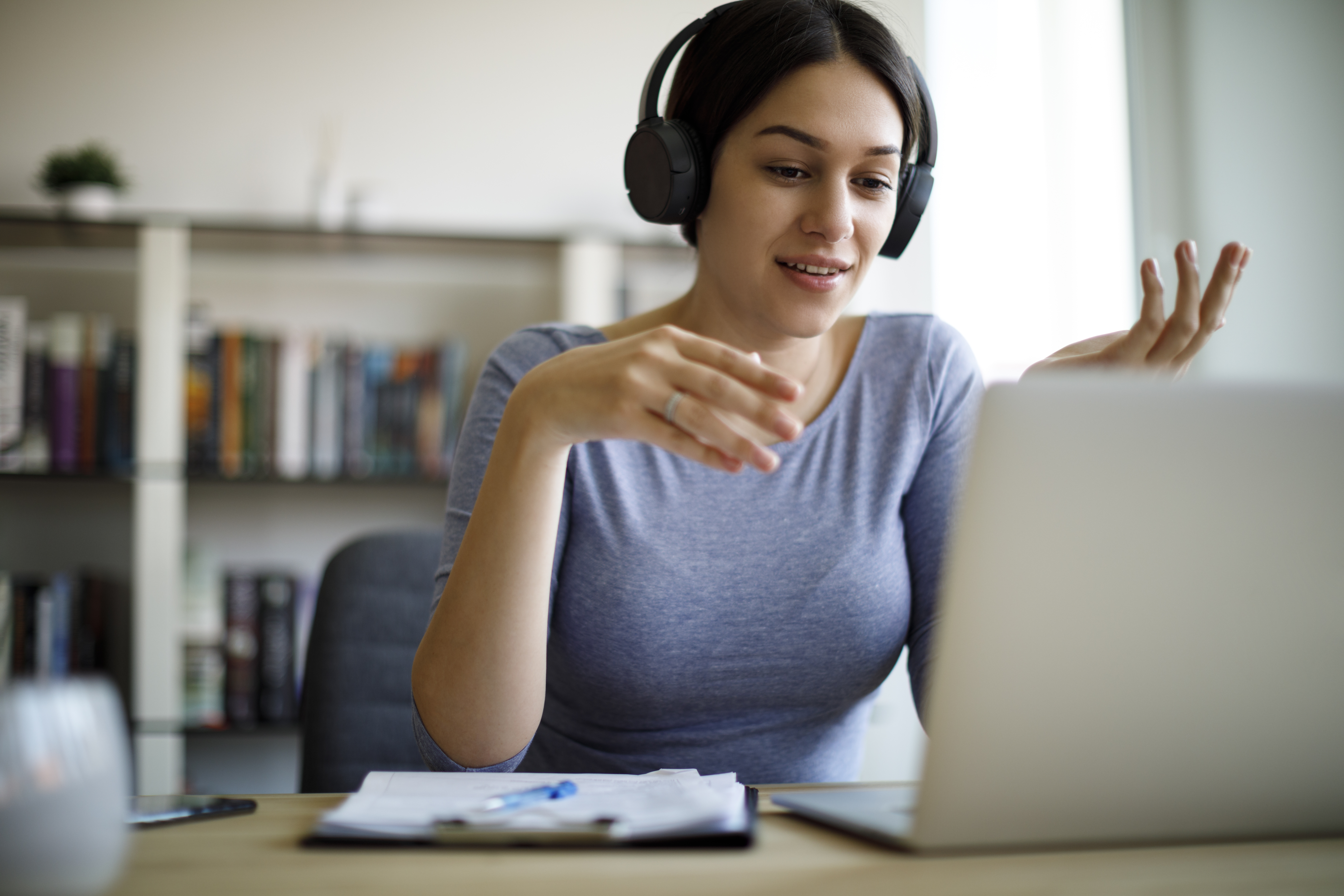 A woman on a Zoom call on her laptop wearing headphones