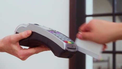 closeup photo of someone holding a device for another person to swipe their credit card to pay