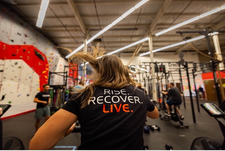 A person wearing a tshirt that says rise recover live working out in the phoenix gym