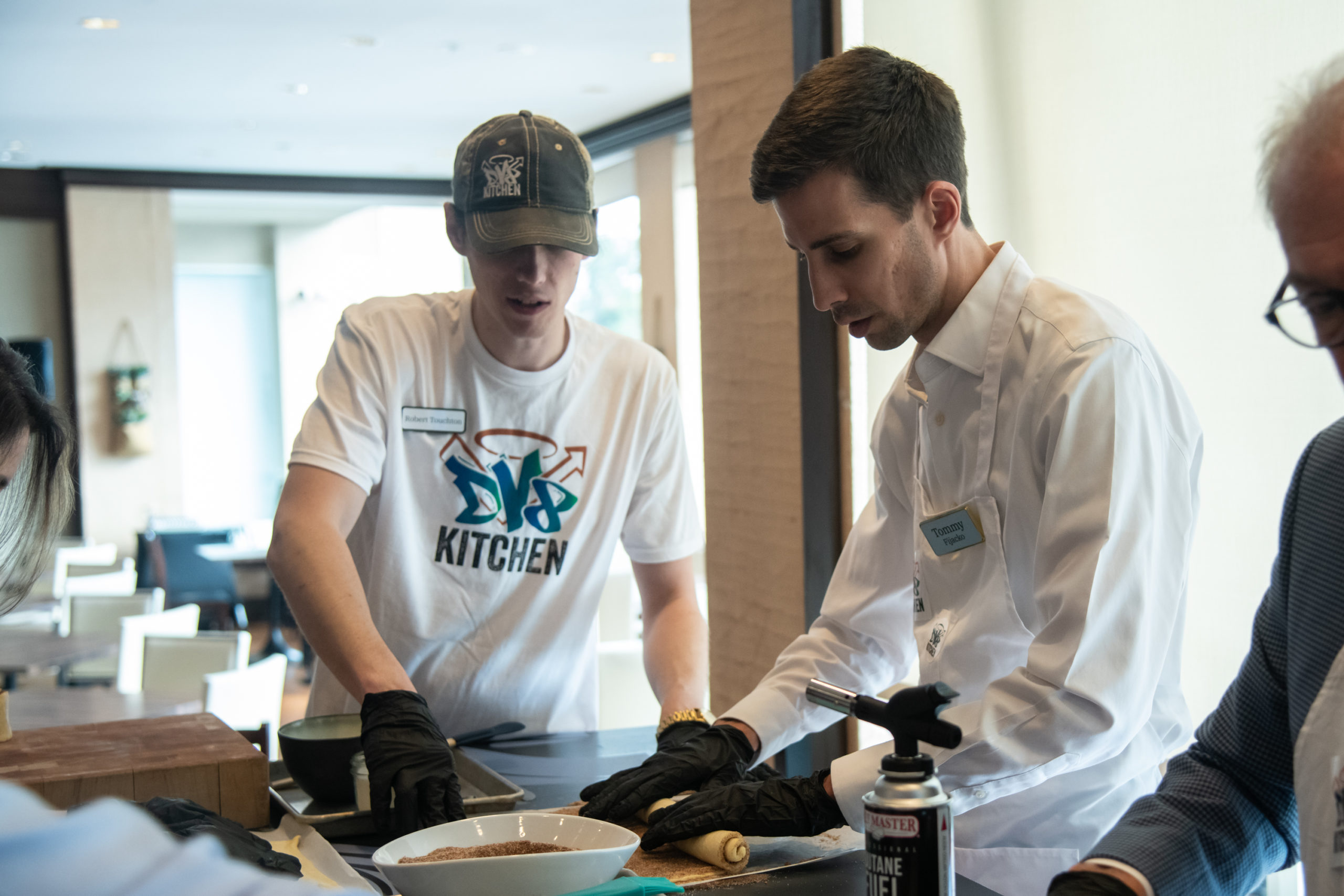 Robert from DV8 Kitchen walks participant Tommy through the dough-shaping process during a cooking demonstration