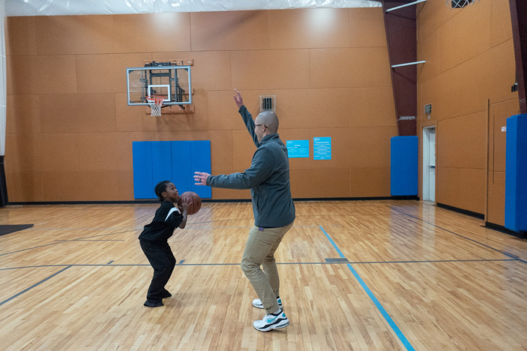 A child playing basketball with a mentor