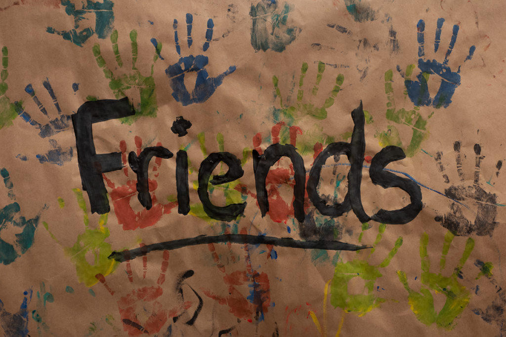 Friends written in paint with paint handprints decorating the background