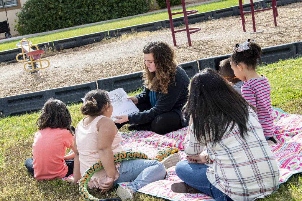 Teacher reading with group of children outside