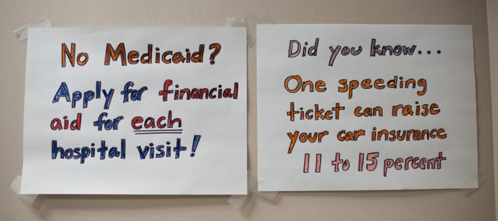 Two pieces of paper taped to a wall with tips on financial aid for medical visits and car insurance