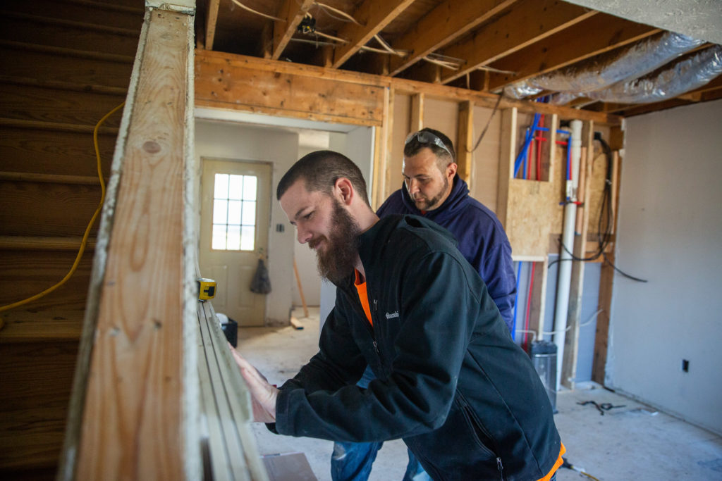 Two men work on construction on a house