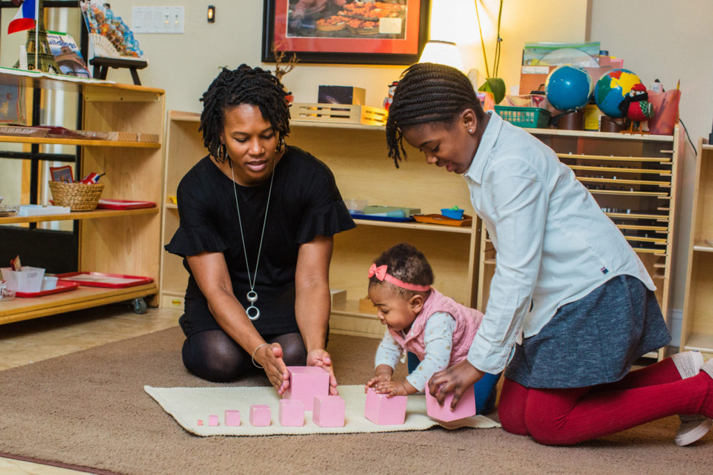 Ms. Myani and a young girl and a baby play with pink blocks