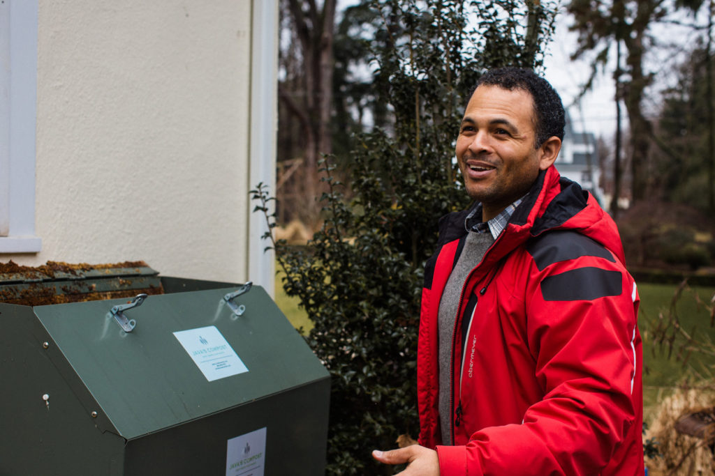 A man smiling in front of composting bin