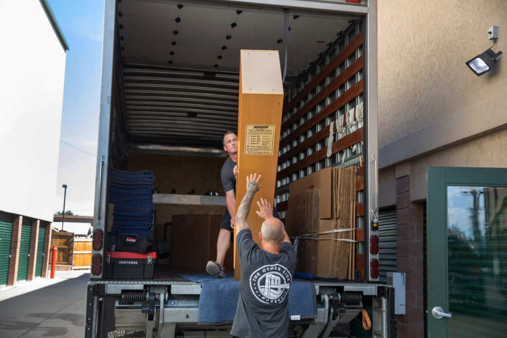 Two men load a shelf onto a moving truck