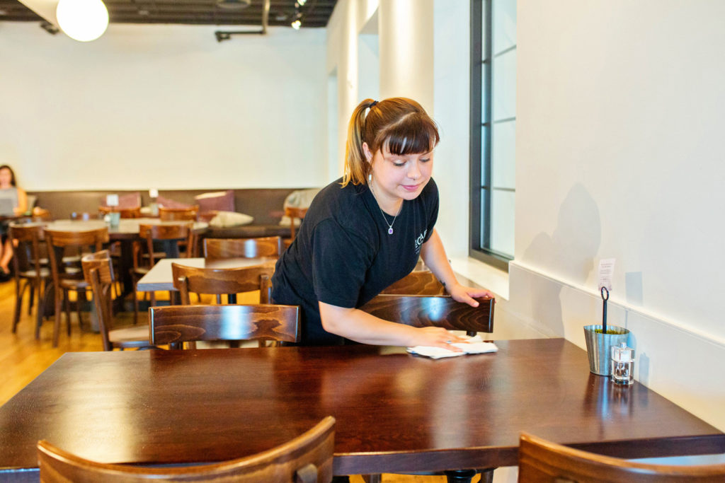 A Thistle Farms Cafe staff member wipes down a table