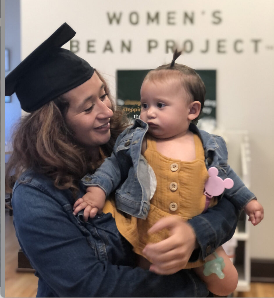 Woman with a graduation cap holding a baby
