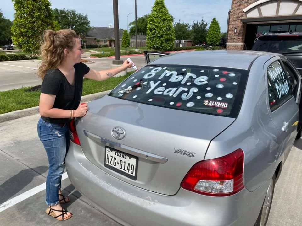 A woman writes with car marker on a rear window