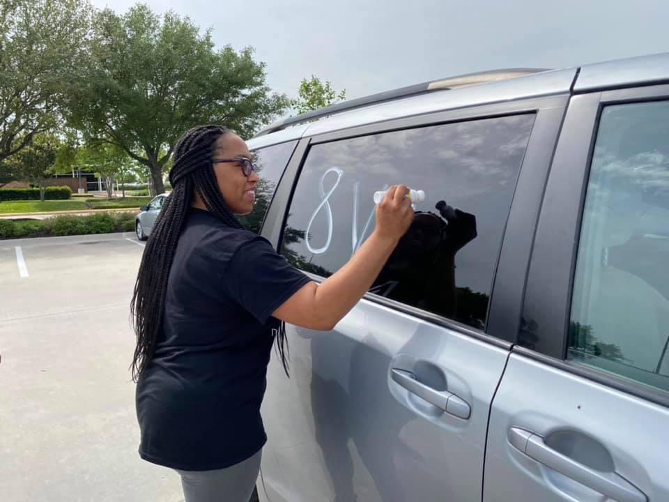 A woman writing on a car window