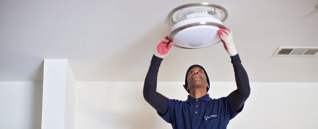 A man takes the cover off of a ceiling light