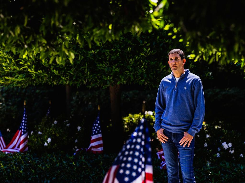 A shot of Alan Smolinisky standing near an American flag