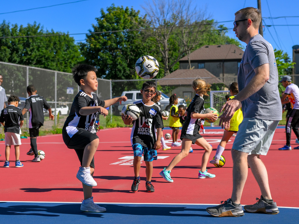 Young soccer players show off their skills to their coach.