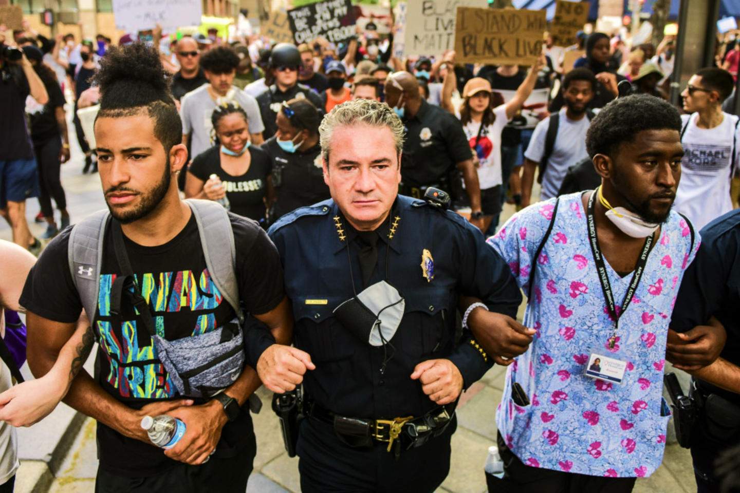 A protest where a police officer is linked arm in arm with someone in scrubs