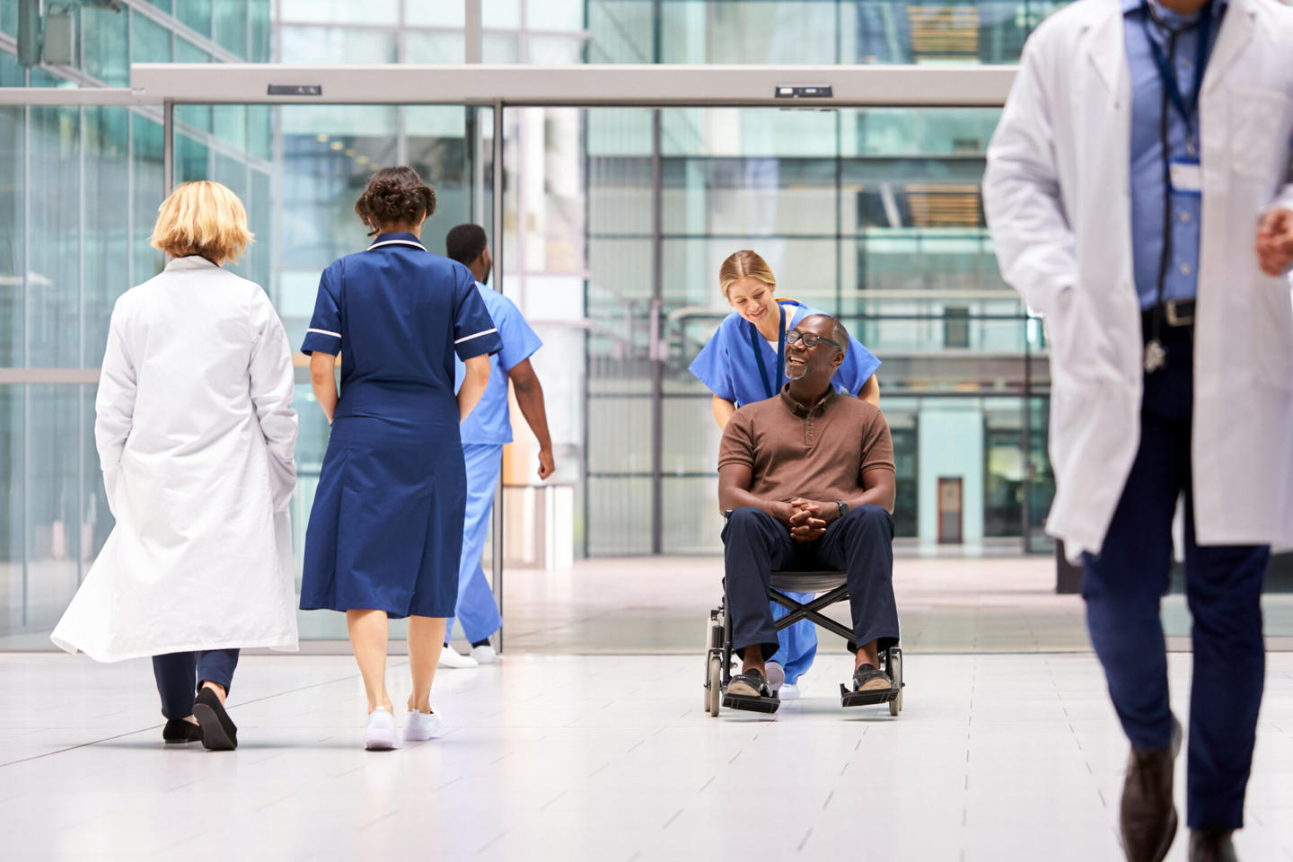 A nurse pushes a man in a wheel chair in a hospital