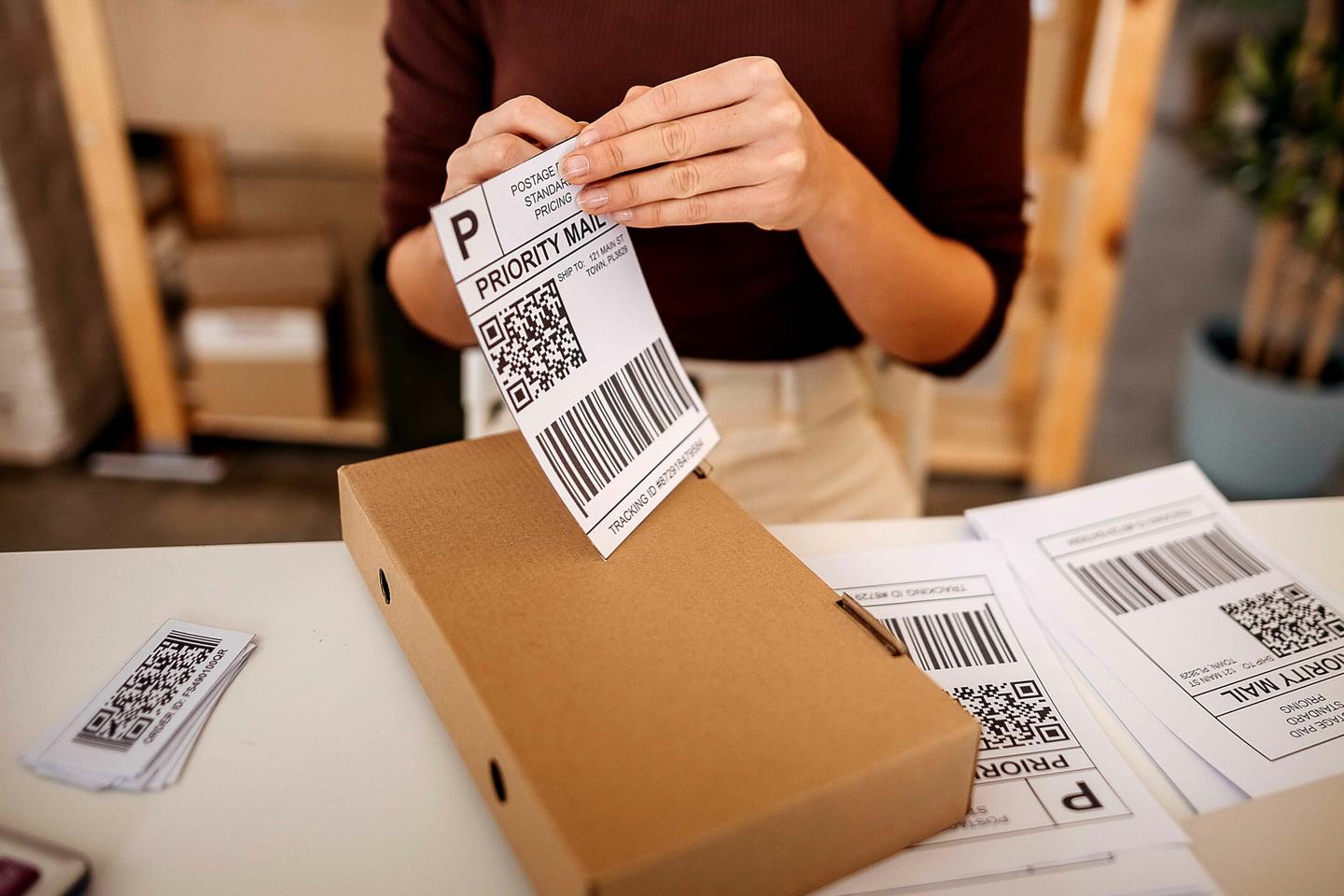A woman placing a shipping label on a box