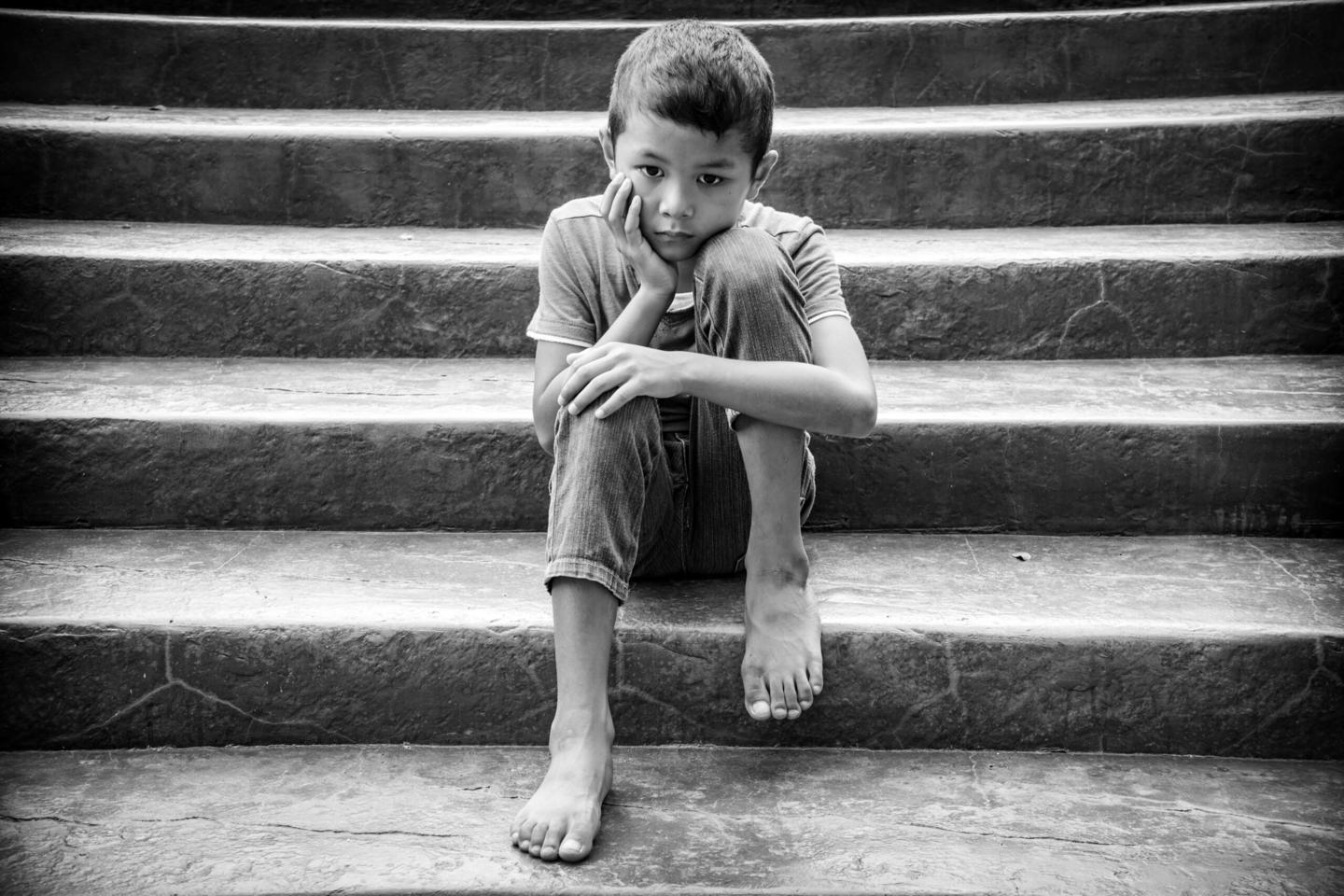 A child with no shoes sits on steps