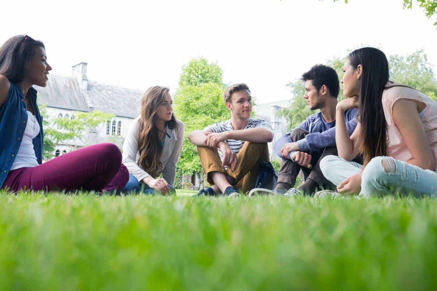 College students sit outside together talking on campus