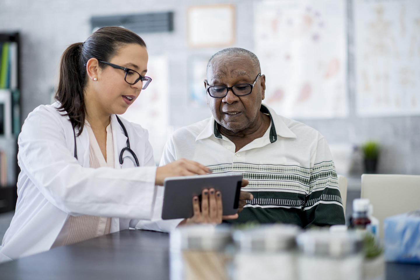 A doctor explains something on a tablet to an older gentleman
