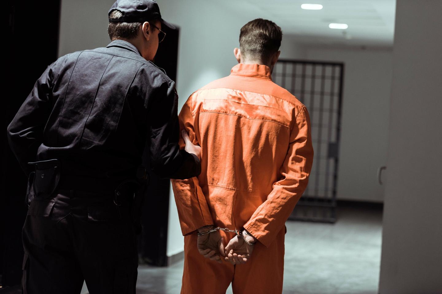 A corrections officer guides an inmate through a correctional facility