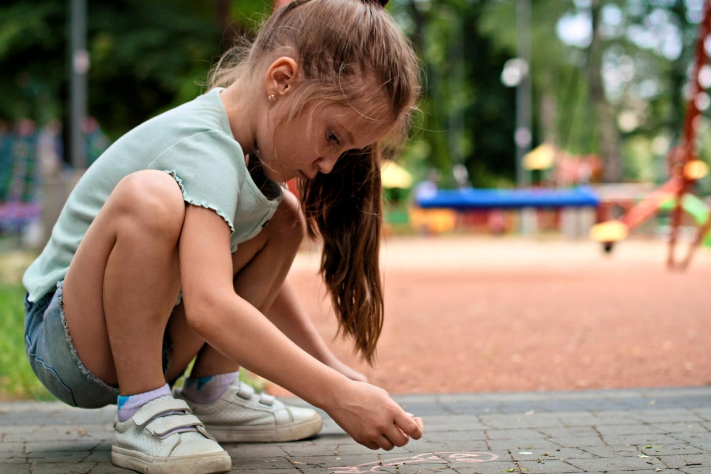 Child playing with chalk in a park