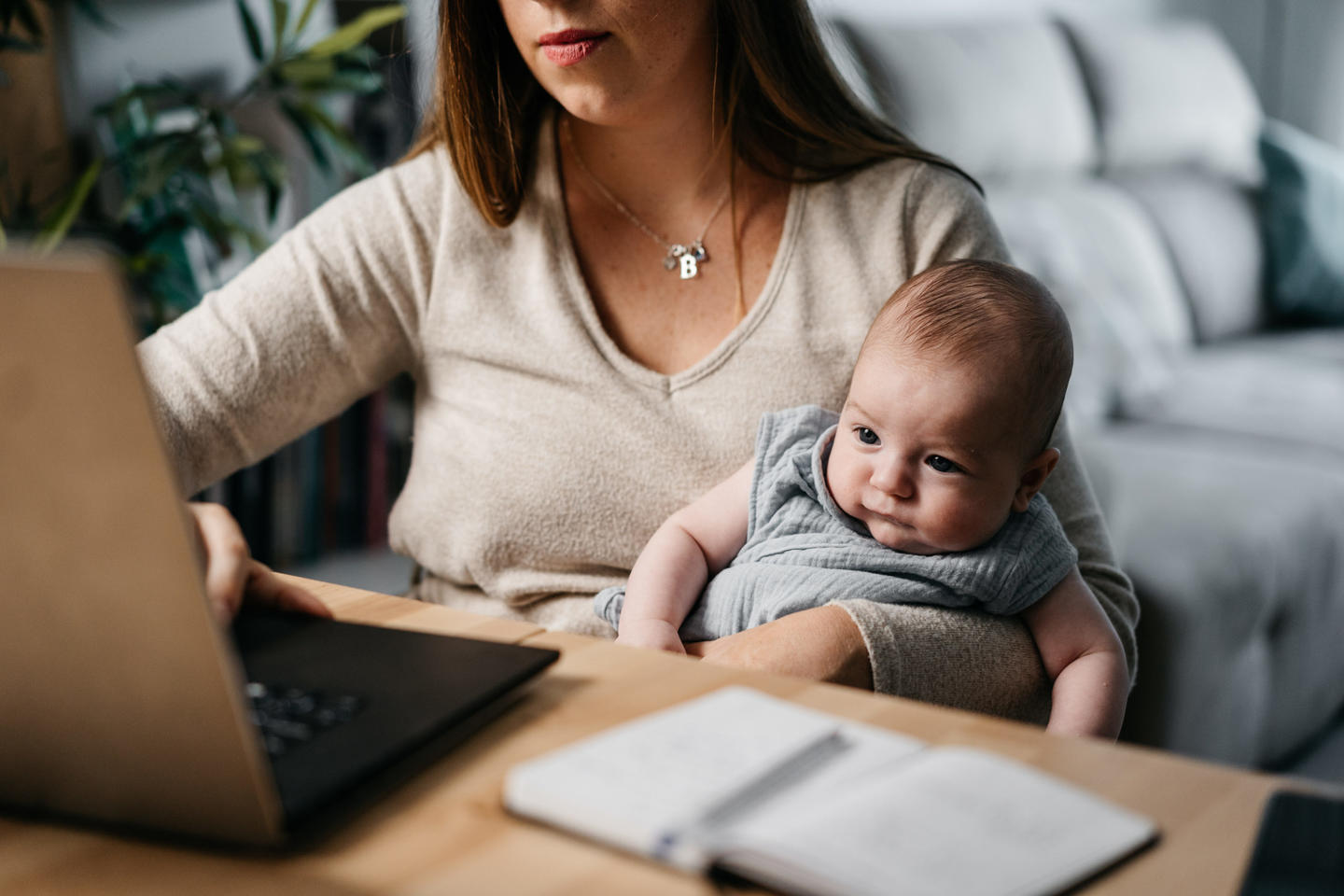 A woman on a laptop holding a baby