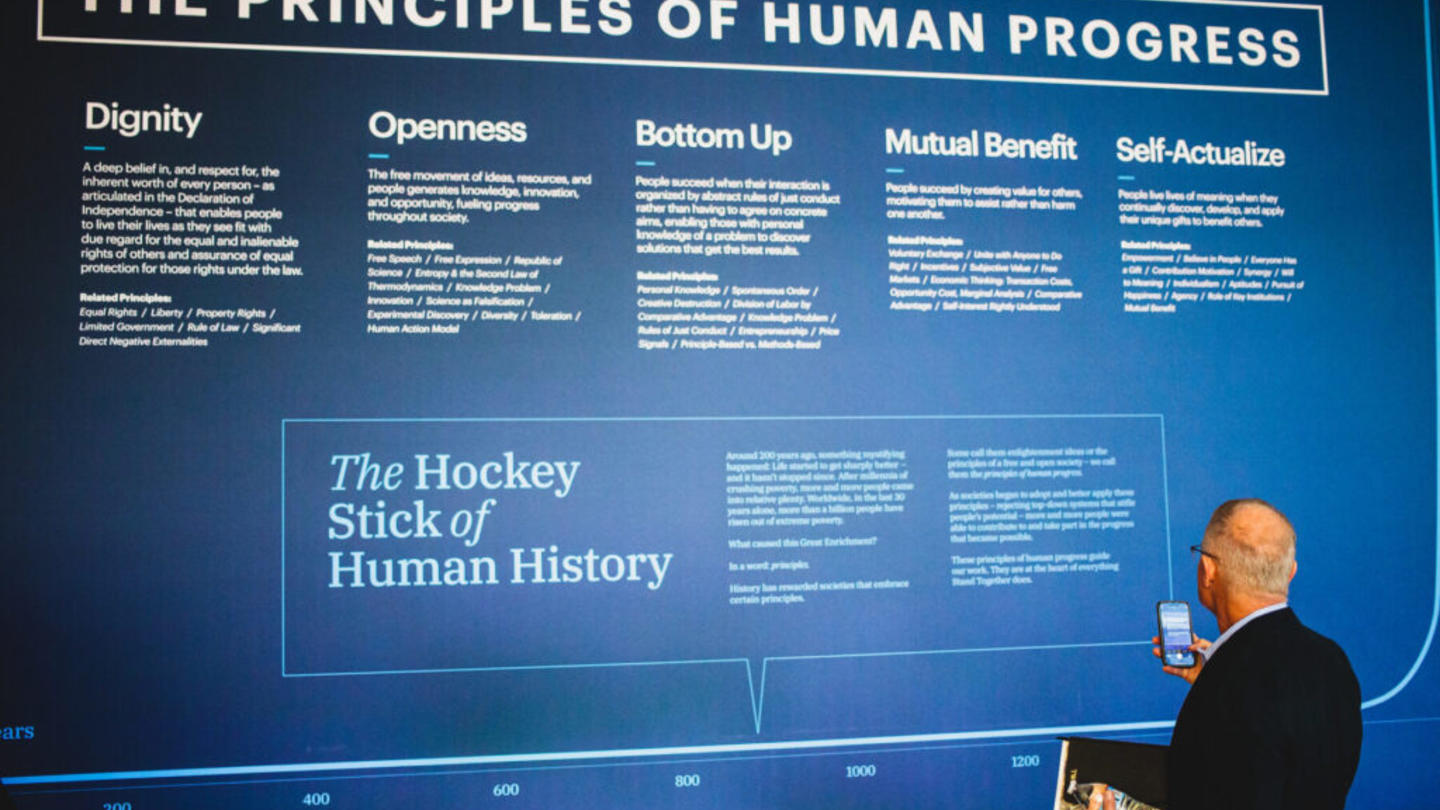 A man looking at an event exhibit articulating the principles of human progress
