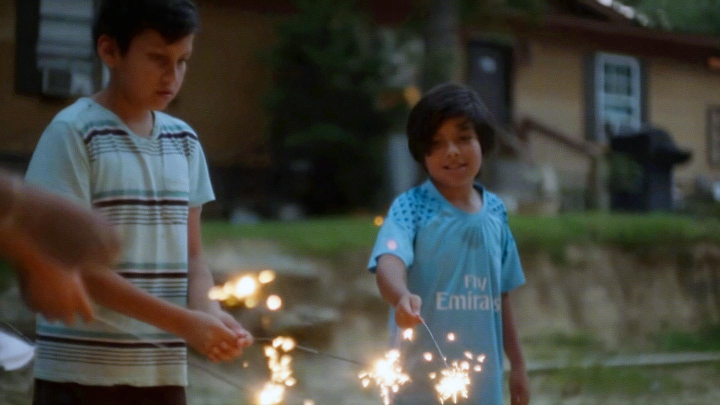 Two children stand next to each other holding sparklers