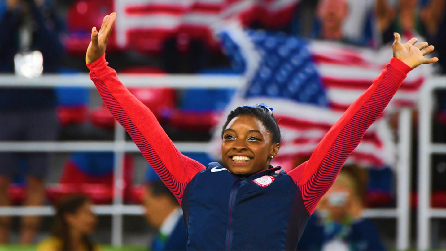 Gymnast Simone Biles with her hands in the air