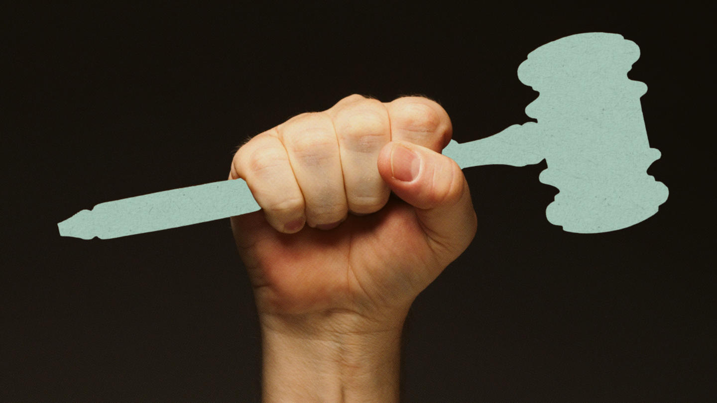 A person's hand holds a gavel up in the air.