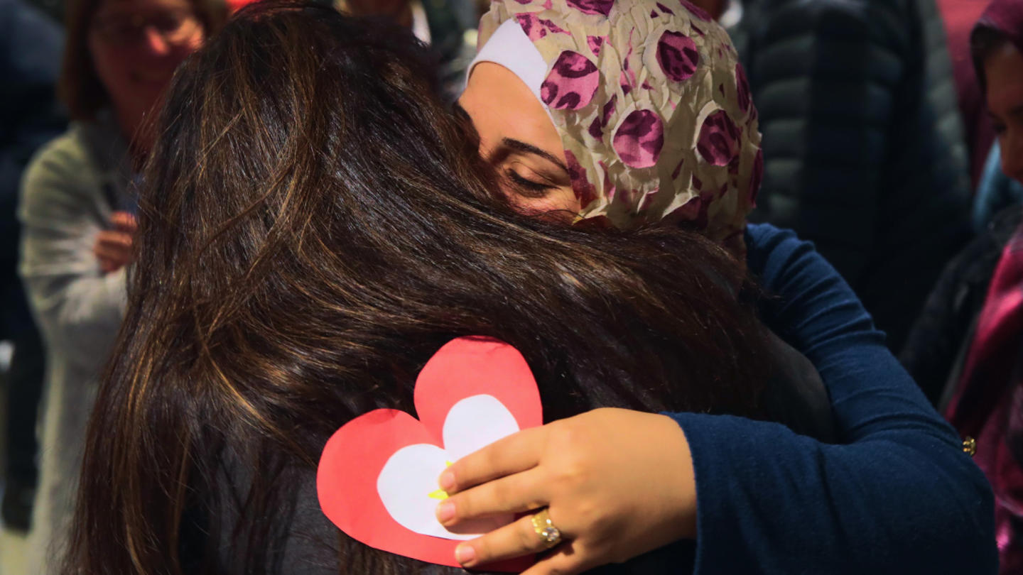 A refugee and an American citizen embrace one another