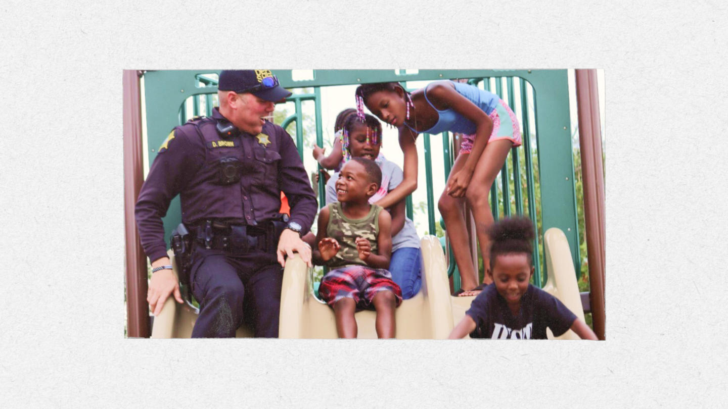 A police officer plays with children on a slide.