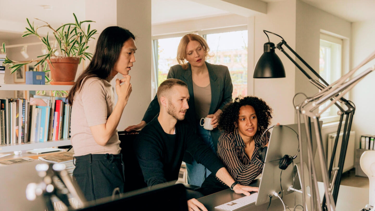 A group of individuals hovering around a computer screen