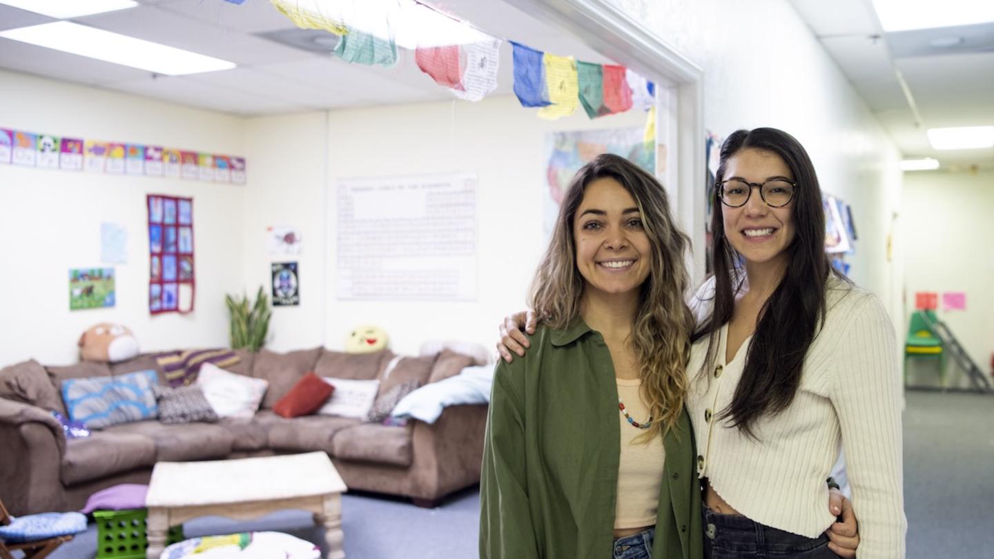 Two teachers standing next to each other arm in arm