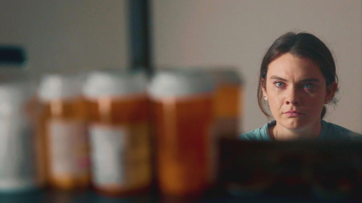 A woman looking at several pill bottles in a medicine cabinet