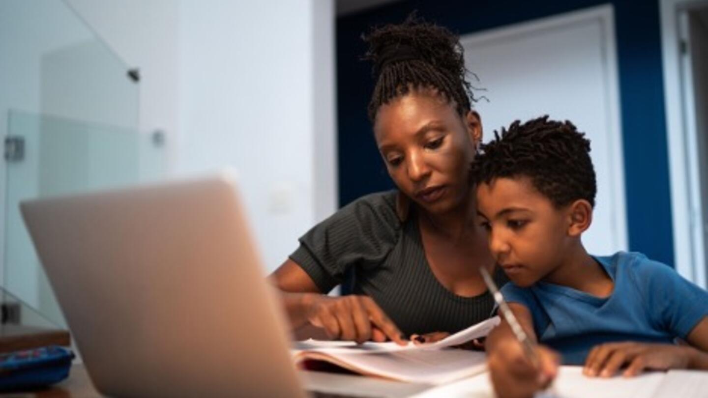 Parent and child use a personal AI tutor on a laptop to complete schoolwork at home.