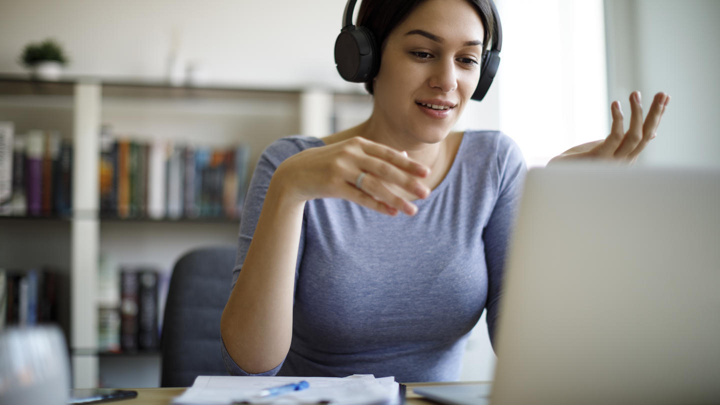 A woman on a Zoom call on her laptop wearing headphones