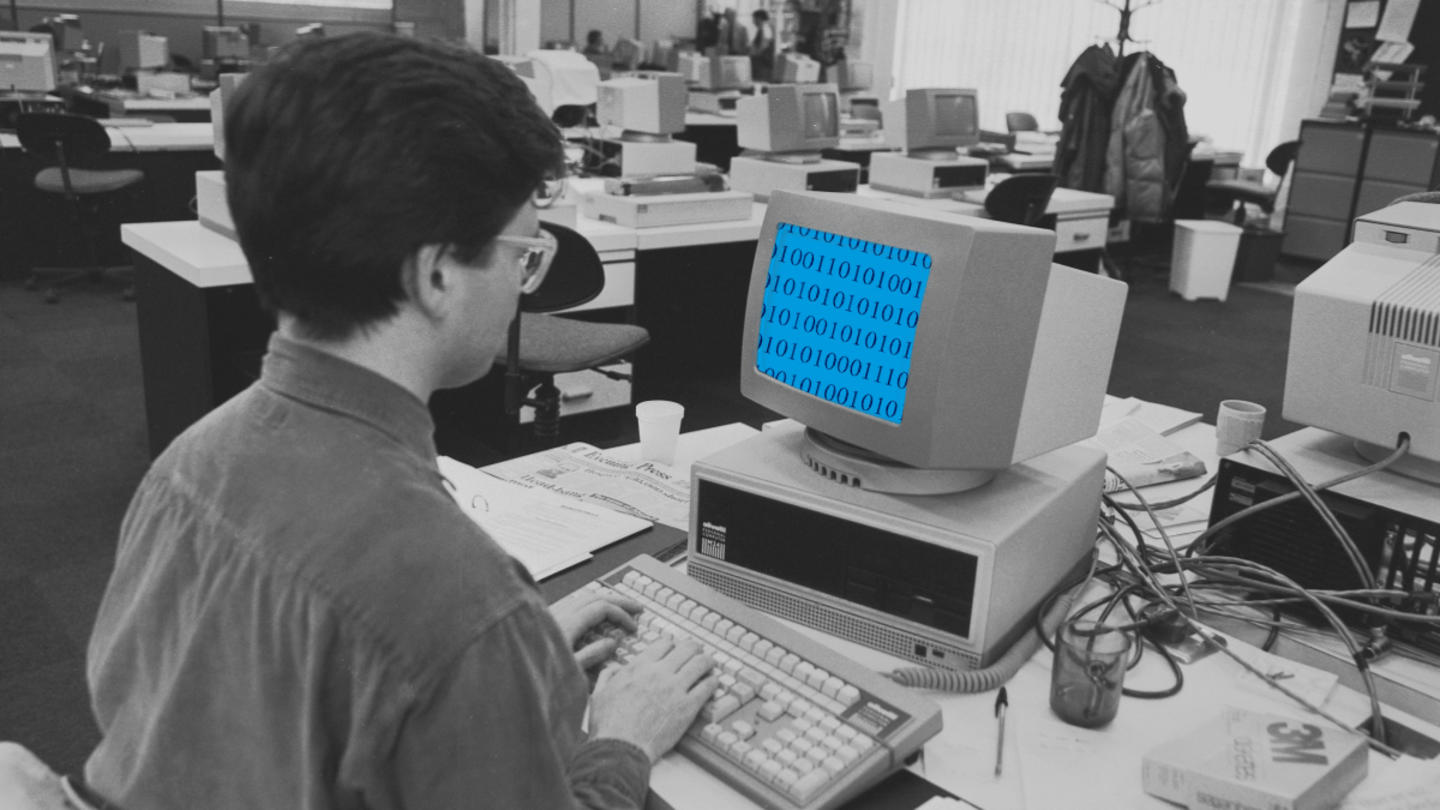 A black and white photo of a guy using an old fashioned computer with a blue screen showing binary code as a stylistic element