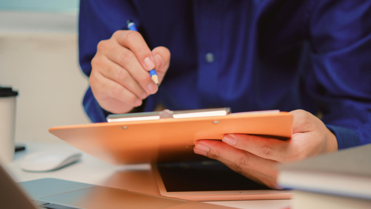 A person wearing a blue shirt holding a clipboard