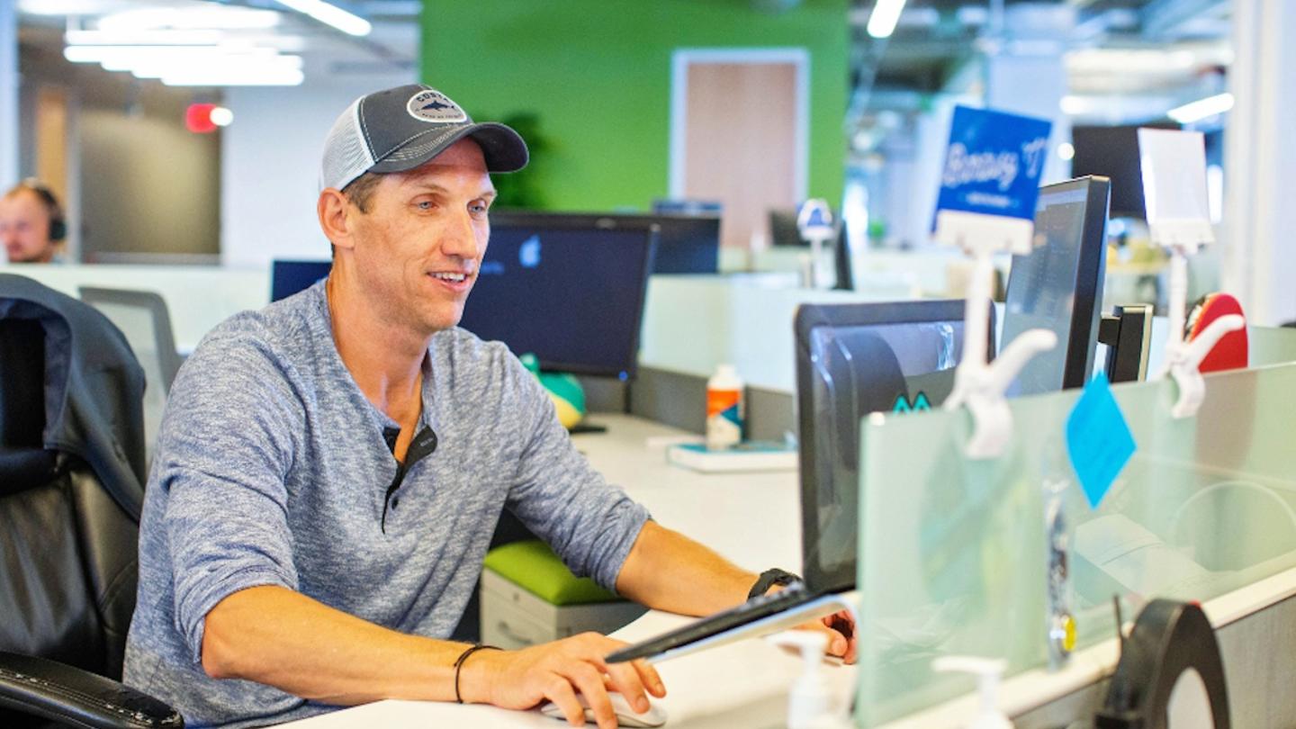 Person wearing a hat, working on a computer, focusing on a task.