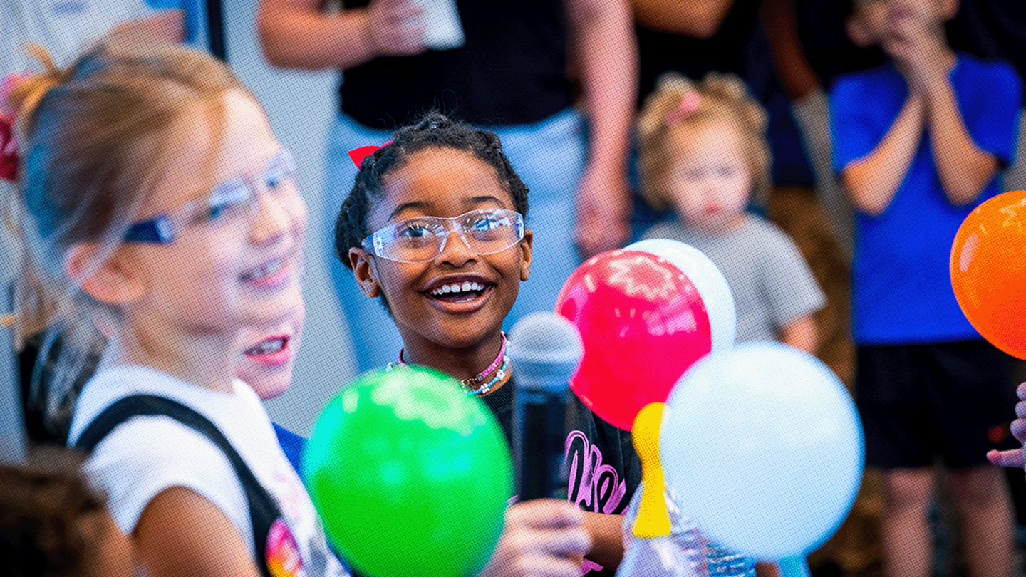 Students wearing science googles holding colorful balloons