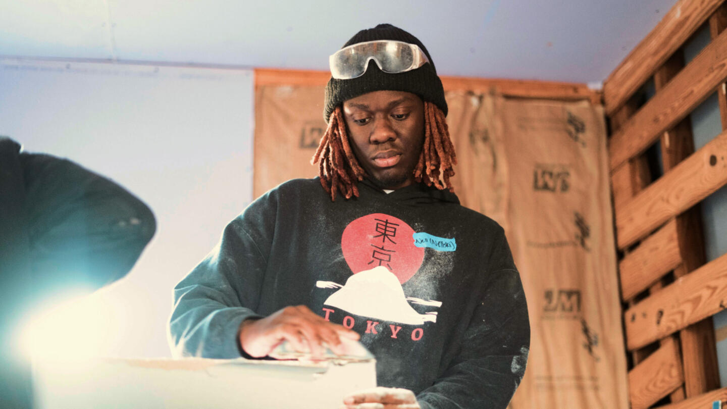 Volunteer with safety goggles on his head while sanding wood.