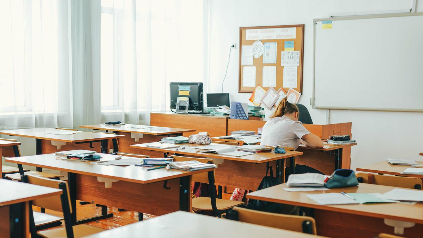 A student sits in a classroom working at a desk