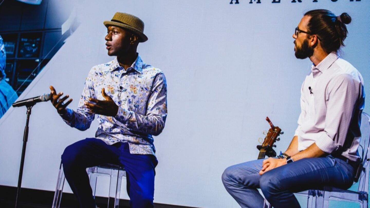 Two speakers express their right to free expression, talking on a stage with a microphone.