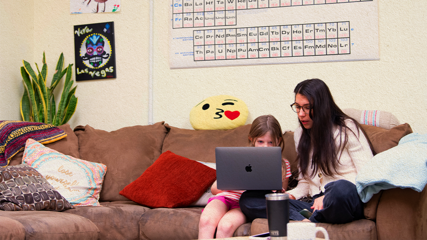 Mother and child sitting on a couch looking at a laptop.