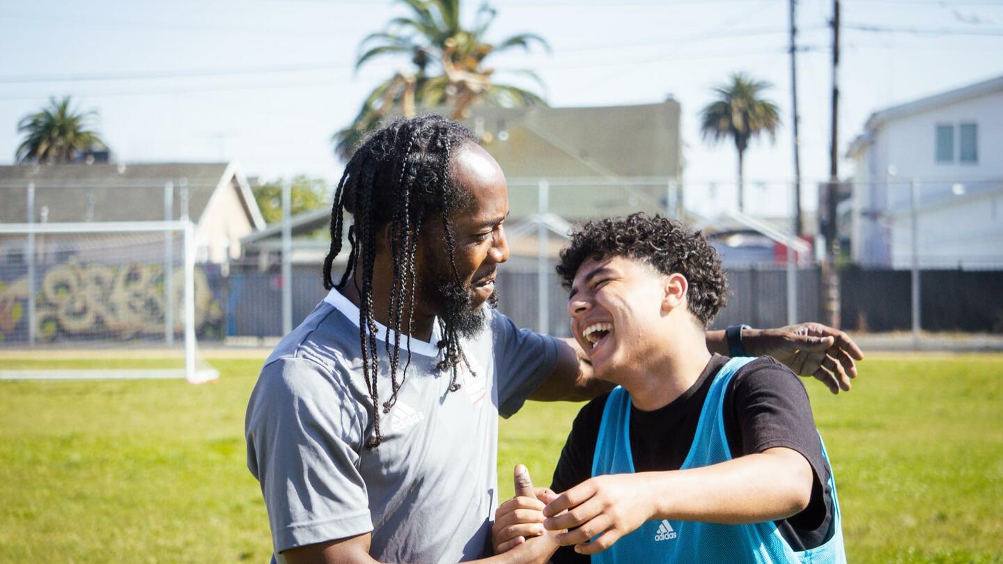 Smiling Coach embracing happy soccer youth player